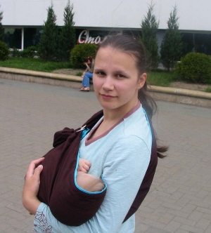 Ребенок спит в колыбельке в кольцевом слинге